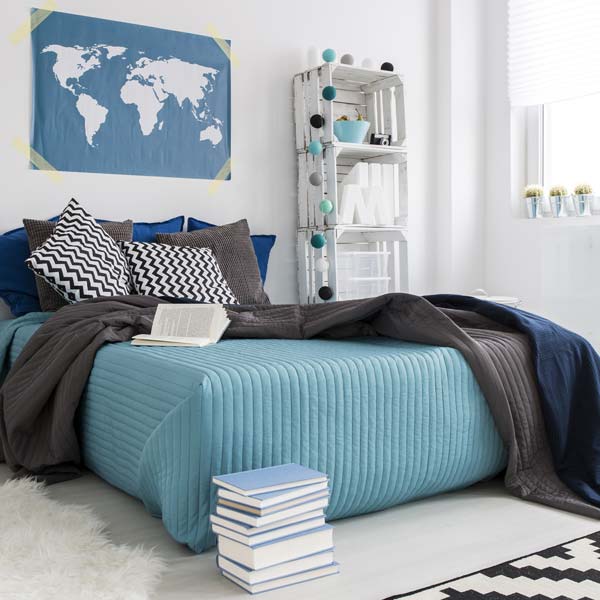 Bedroom with a bed with blue striped bedsheets and dark grey an dblue throws.