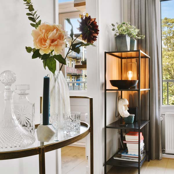 Close up of an open shelf unit with vases, books, flowers and lights styled on it.