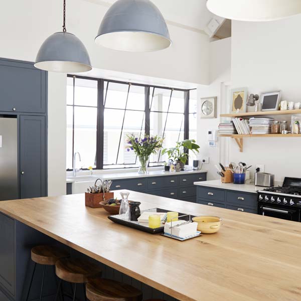 Modern country styled kitchen with a beech wood countertop and dark blue cupboards.